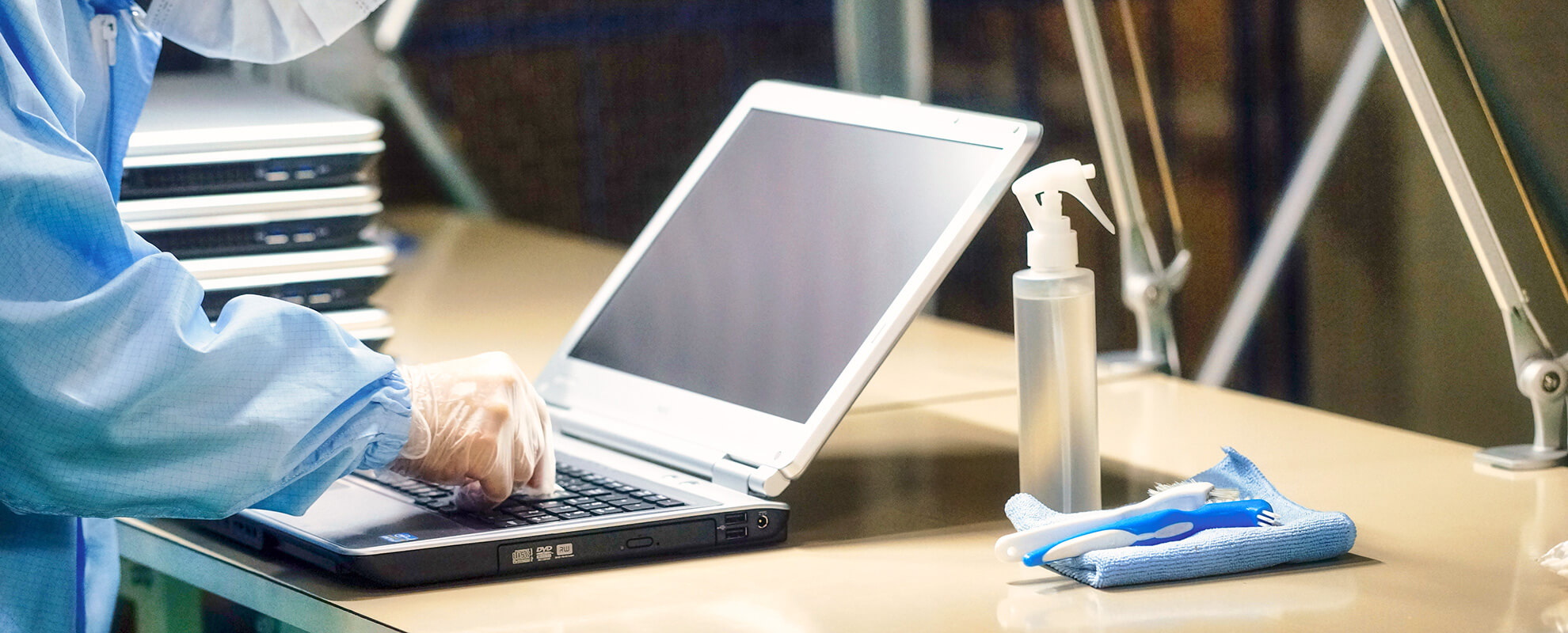 デスクの上でノートパソコンを清掃するスタッフ