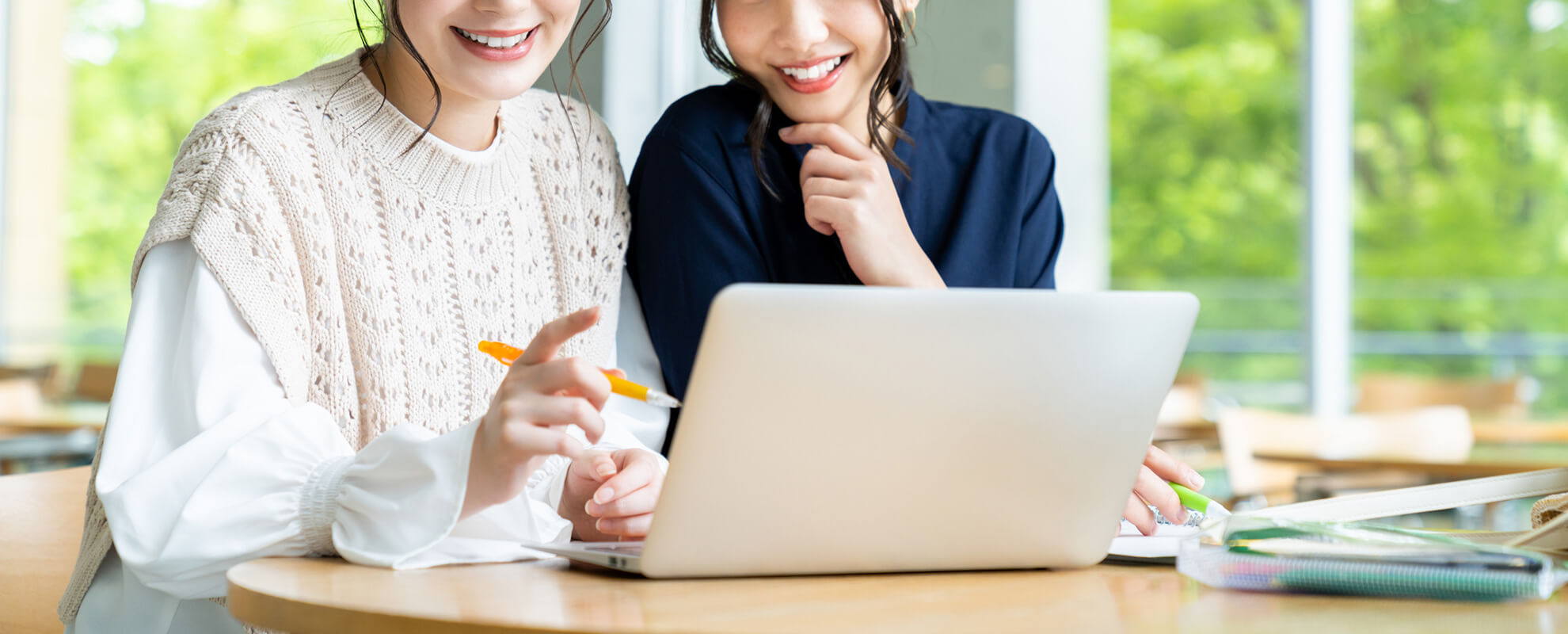 ノートパソコンの前で談笑する2人の女性