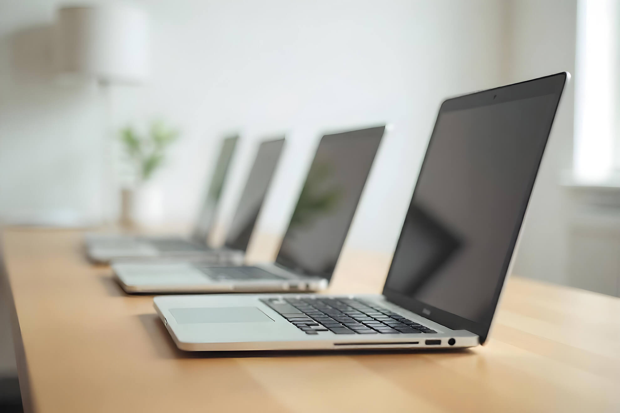 デスクの上にキレイに並んでいる4台の開いたノートパソコン